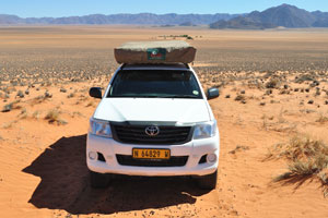 The Toyota Hilux 4x4 is parked at the foot of dune, Farm Gunsbewys is on the background