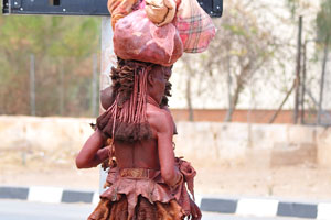 Herero women are standing with their luggage on the heads