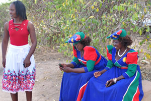 Herero women with the mobile phones are dressed in the national clothes