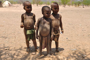 Little Himba boys are standing with sweets in the hands