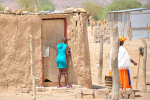 An African woman tries to unlock a clay hut