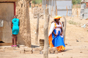 A Herero woman with a baby wears an orange hat