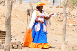 A Herero woman is hanging clothes to dry on clothesline