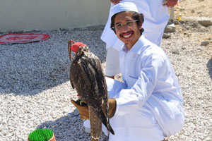 A smiling hunter with a falcon on his hand in the city of Madīnat ash Shamāl