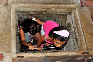 A mother and her little girl are climbing the stairs through the narrow opening to get to the top of the tower of Guaita fortress