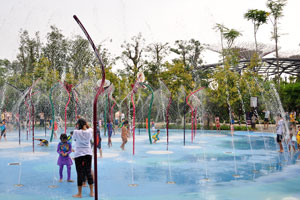 Children play under the rotating fountain