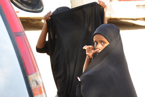 Young Somali girl jokingly has covered her face, as if she wants to hide from us