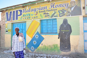 Malaysian honey and Saudi fashion, a black cloak is depicted on the shop's wall