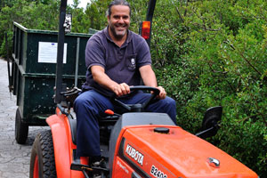 A garden's employee is driving on the Kubota B2400 compact utility tractor