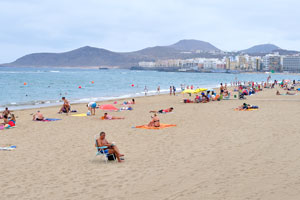 A man is reading a book on the beach of Las Canteras