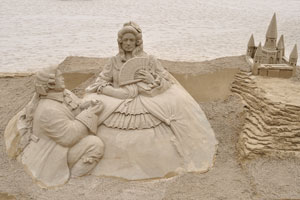 Sand sculptures of people are on the beach of Las Canteras