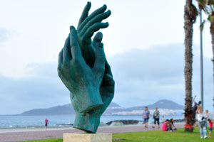 The sculpture of hands is located near the square of “Plaza de la Música y de la Sociedad Filarmónica de Las Palmas de Gran Canaria”