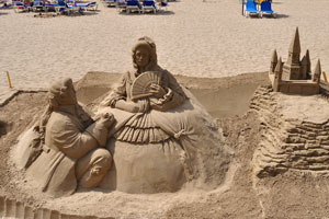 Sand sculptures and a sandcastle are on the beach of Gran Playa Canteras