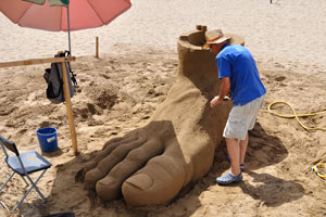 The sand sculpture of a human foot is on the beach of Gran Playa Canteras