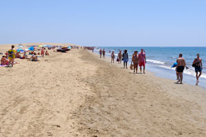 There are a lot of people walking in both directions on Maspalomas beach
