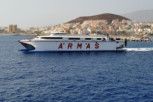 Naviera Armas ferry crossing the ocean is photographed on the background of Los Cristianos town