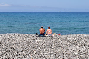 A couple staring at the ocean is sitting on Playa Honda shingle beach