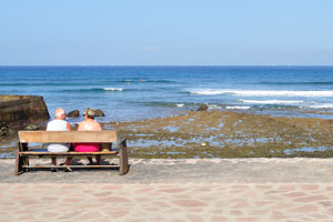 Elderly married couple sitting on a seafront bench