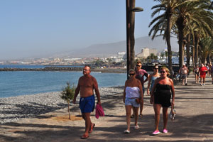 Tourists are walking along Playa de las Américas beach