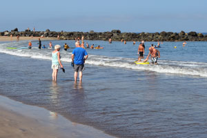 Elderly couple is standing with ankles in the water of Playa de Troya beach
