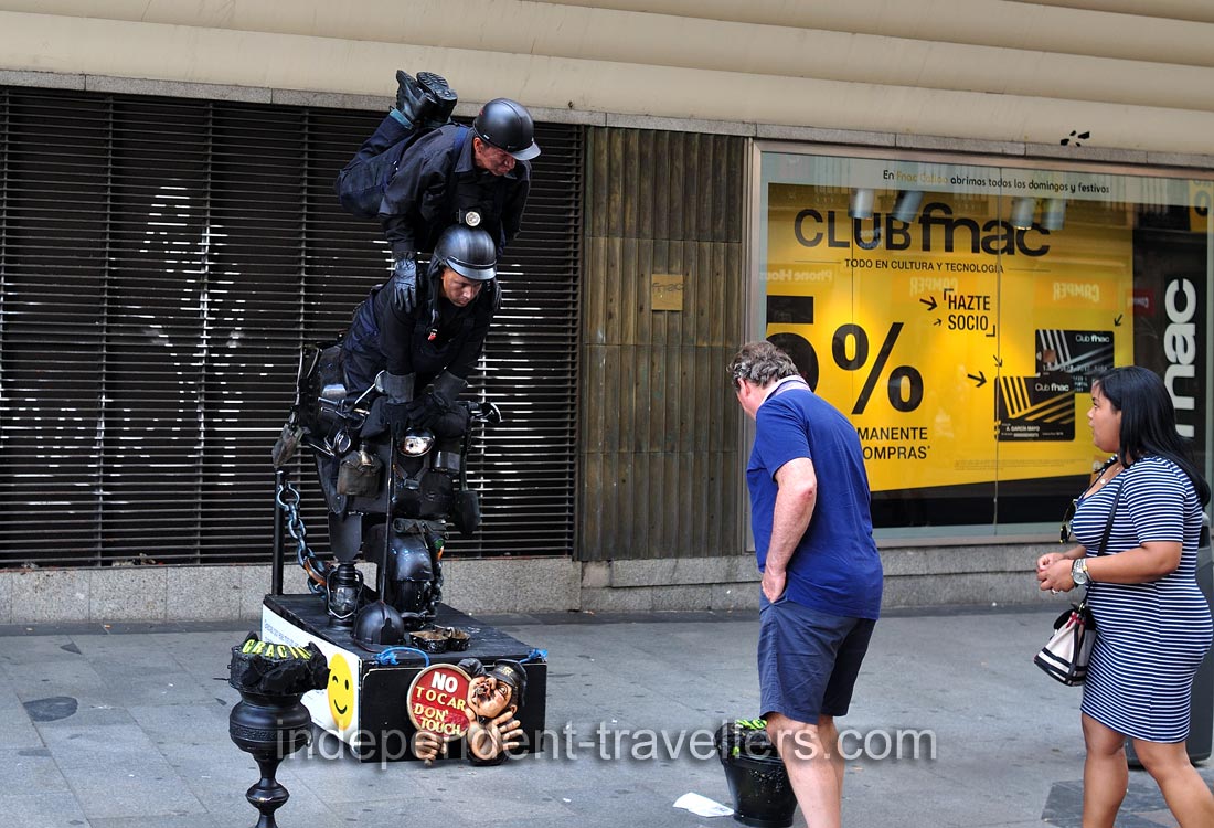 A man gives a donation for street performers on Calle de Preciados street