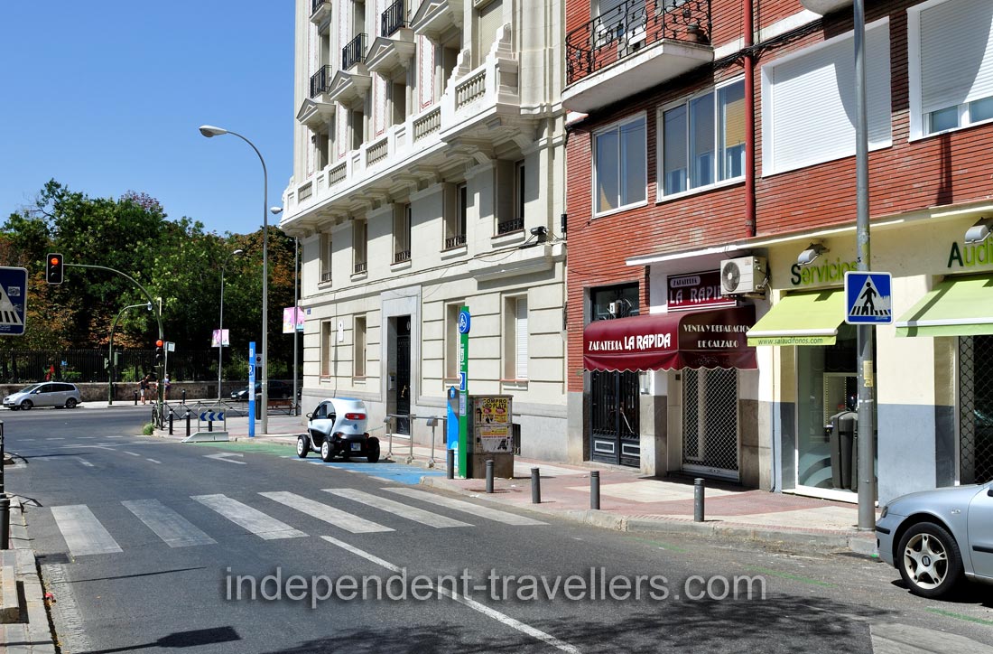 The Renault Twizy is charging at a carsharing station on Calle de Ibiza #1 in Madrid, it is close to the eastern wall of Buen Retiro Park