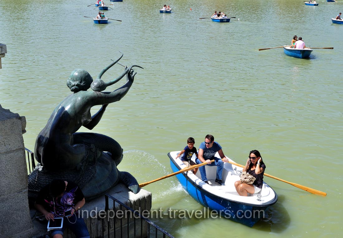 A rowboat with a happy family floats in Estanque Grande del Retiro pond at the foot of King Alfonso XII monument