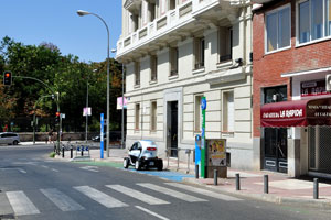 The Renault Twizy is charging at a carsharing station on Calle de Ibiza #1 in Madrid, it is close to the eastern wall of Buen Retiro Park