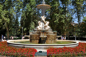 Fuente de los Galápagos fountain is surrounded by red flowers