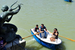 A rowboat with a happy family floats in Estanque Grande del Retiro pond at the foot of King Alfonso XII monument