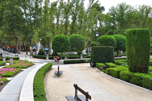 There are neatly trimmed shrubs in Plaza de Oriente park