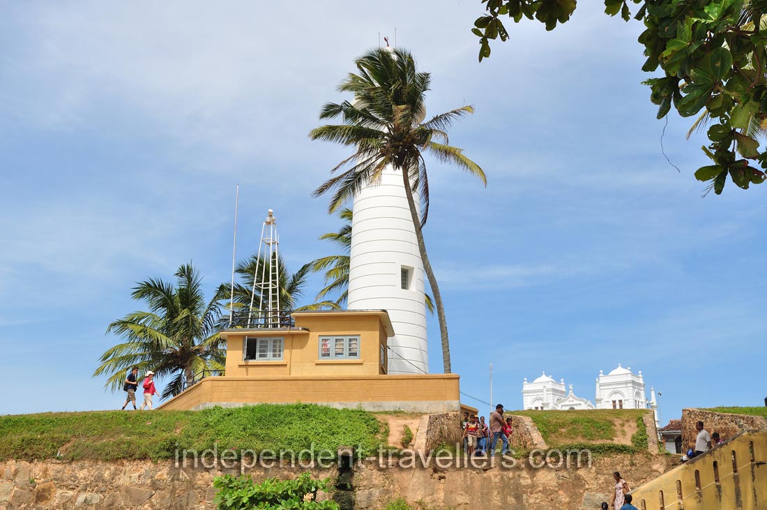 The Galle Lighthouse is hidden behind a palm tree