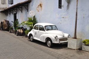A white vintage automobile is parked on Pedlar Street