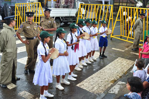 A school dance group performs while a group of policemen stands behind them