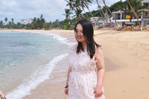 A charming chinese lady in a white dress is on Mirissa beach