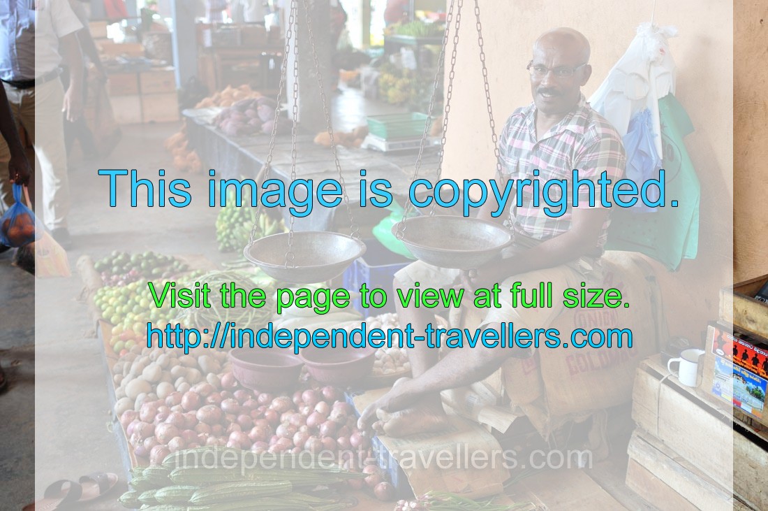 A smiling male vendor is at the fruit and vegetable market