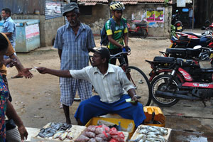 A male fish vendor is at the entrance to the fish market