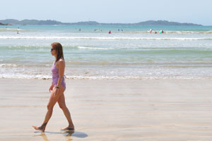 A woman walks along the shore of Weligama Beach