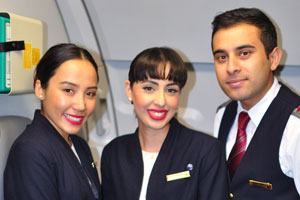 Two lovely female flight attendants strike a pose with a handsome male flight attendant