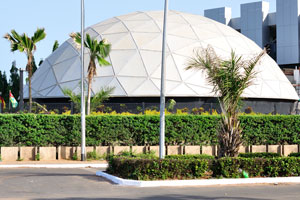 A large building in the shape of a hemisphere is located at the foot of Radisson Blu Hotel
