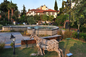 A wooden goat statue is on the background of the fountain in Kecili Park