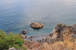 Some people swim in the sea at the foot of a cliff below the observation platform