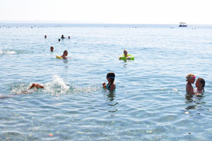 People dive into the crystal clear waters of Konyaalti Beach
