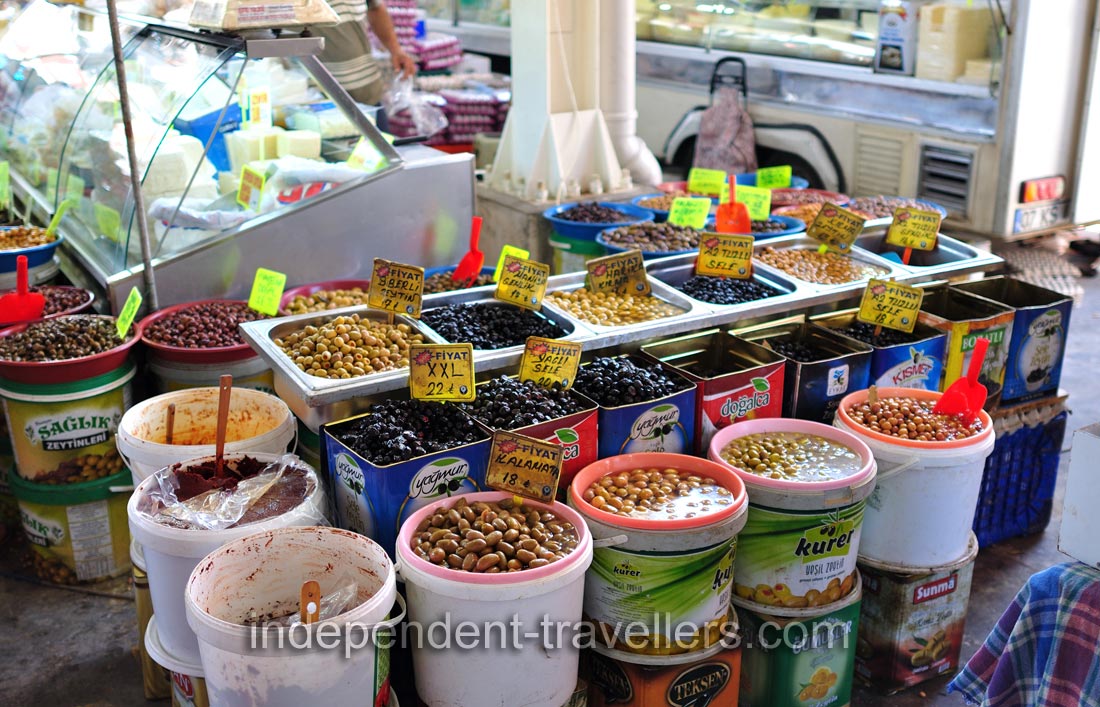 Different species of olives are for sale in opened containers