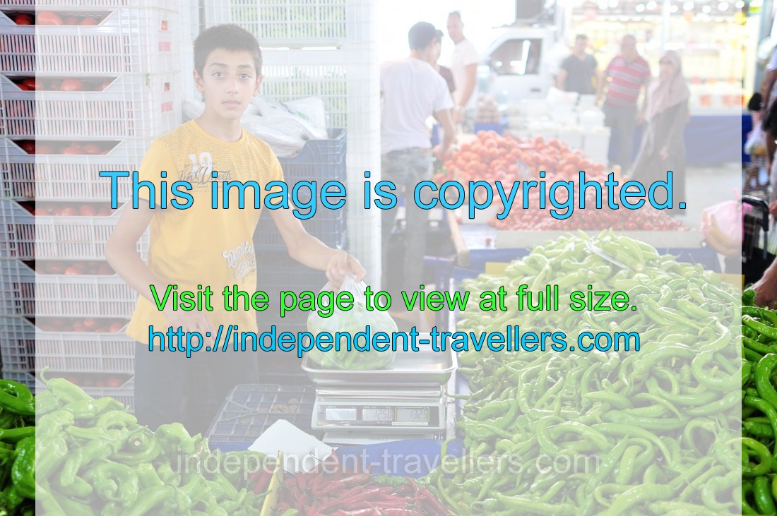 A young boy sells green pepper