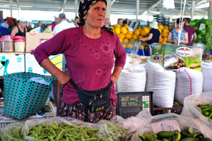 A female vendor sells green beans and cucumbers for 1 turkish lira per 1 kg