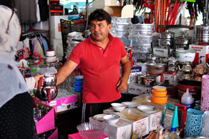 A male vendor sells kitchen utensils