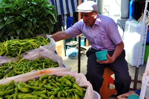 A male vendor selling green pepper