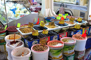 Different species of olives are for sale in opened containers