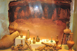 A big photograph of a burial chamber with pottery scattered around it